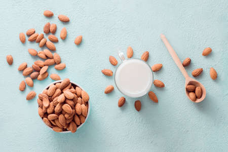 Peeled almonds in a bowl and almond milk in a glass on a light background. Alternative nutrition, source of vitamins. Top viewの写真素材