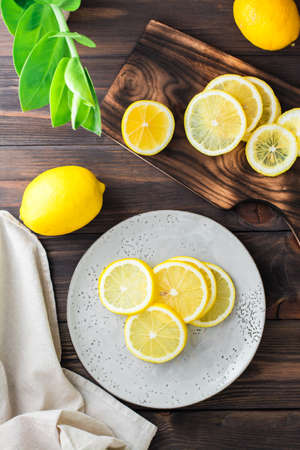 Round pieces of ripe lemons on a plate and on a wooden cutting board on the table. Organic nutrition, source of vitamins. Top and vertical viewの写真素材