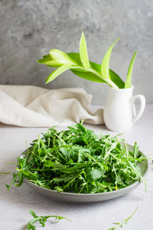 Fresh leaves of arugula on a plate on the table. Organic diet vegetarian food. lifestyle. vertical viewの写真素材