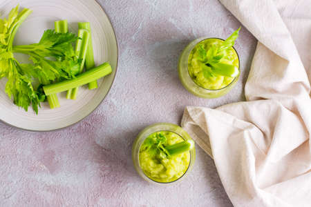 Fresh celery smoothie in glasses and cooking ingredients on the table. Vegetarian diet detox food....