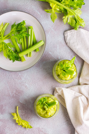 Two glasses with fresh celery smoothie and cooking ingredients on the table. Vegetarian detox diet food. Top and vertical viewの写真素材
