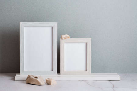 Eco friendly home decor two photo frames and stones on the table on a gray background. pastel shades
