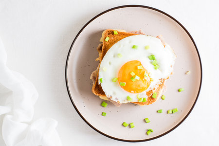 Croque madam sandwich with cheese, ham and egg on a plate on a light table. Hearty homemade breakfast. top view. close-upの写真素材