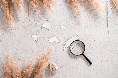 Flat lay concept travel. Continent templates and magnifying glass in grass cover on textured...