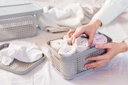 Women's hands neatly fold towels in a clothes drawer. Organization and order at home.の写真素材
