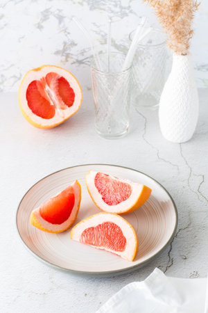 Pieces of juicy fresh grapefruit on a plate on a light table. vitamin diet food. vertical viewの写真素材