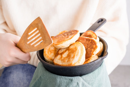 The child holds in his hands a frying pan with pancakes and a spatula for frying. Lifestyle with foodの写真素材