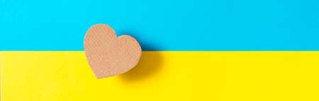 The concept is no war in Ukraine. Cardboard heart on the background of the Ukrainian flag. top view....