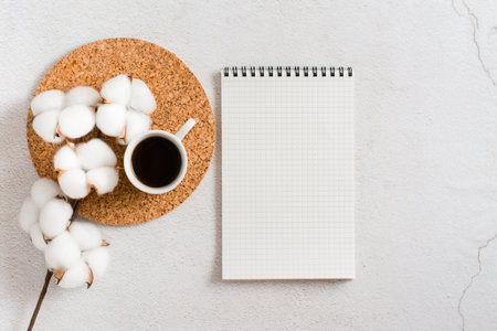 A cup of coffee, a cotton branch and an empty notebook on a light background. planning and goals. Eco lifestyleの写真素材