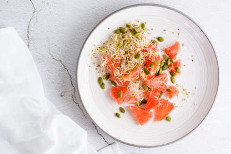Fresh salad of grapefruit, clover and alfalfa sprouts and pumpkin seeds on a plate on the table. Organic vegetarian detox food. top view. close-upの写真素材