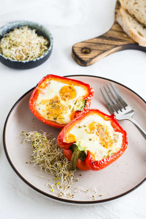 Ready-to-eat bell pepper halves baked with egg and microgreens on a plate on the table. Healthy organic diet. vertical viewの写真素材