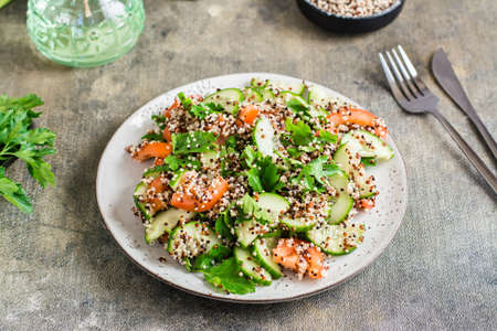 Appetizing salad of cucumbers, tomatoes, a mixture of quinoa and parsley on a plate on the table. Vegetarian foodの写真素材