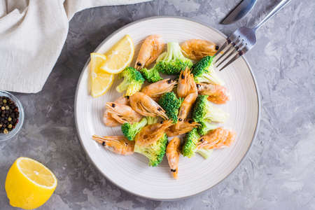 Fried broccoli and shrimp on a plate on the table. Healthy vegetarian food. top view. close-upの写真素材