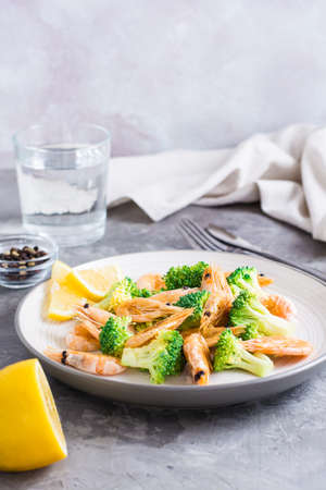 Fried broccoli and shrimp on a plate on the table. Healthy vegetarian food. vertical view. copy spaceの写真素材