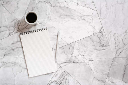 Notepad, pen and cup of black coffee on marble tiles. planning and reminder. Scandinavian house designの写真素材