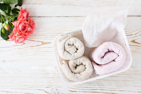 Rolled clean towels in a container and a bouquet of roses. top view. Organization and order