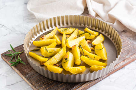 Baked potatoes with garlic and rosemary in a pan on the table. homemade vegetarian dish
