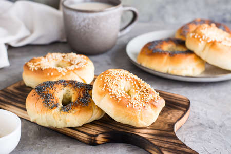 Bagels with poppy seeds and sesame seeds on a plate and a cup of coffee on the table. homemade breakfast.の写真素材