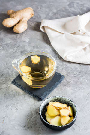 Ginger tea in a cup and chopped root in a bowl on the table. Natural Vitamins. vertical view