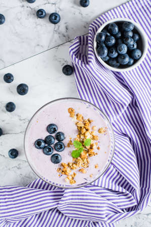 Smoothies with blueberries and granola in a bowl on the table. Organic antioxidant healthy food. Top and vertical viewの写真素材