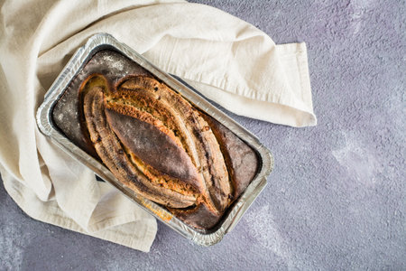 A loaf of baked banana bread in a baking dish on the table. Social media trendy. top viewの写真素材