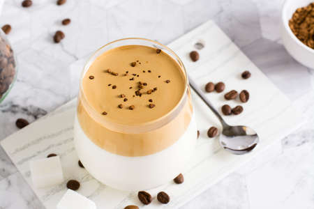 Dalgona coffee - trendy iced Korean coffee in a glass on the table. social media drinks.