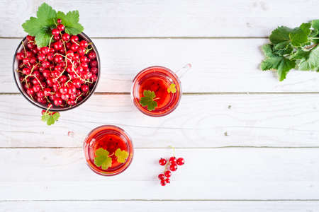 Red currant compote in cups on the table. Homemade summer drinks. top viewの写真素材