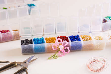 Beaded flower among containers with beads and accessories for work. Needlework and handmade