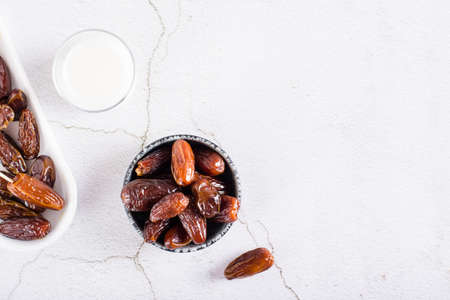 Dates in a bowl and a glass of milk on the table. Food for the holy month of Ramadan. top viewの写真素材