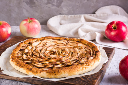 Baked apple tart on baking paper on the table. homemade baking.の写真素材