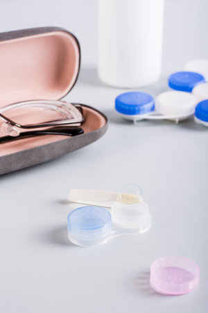 Contact lens on an open storage container on the background of a case with glasses. vertical view