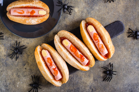 Halloween recipe for hot dogs with sausage fingers in ketchup on a slate on the table. top viewの写真素材