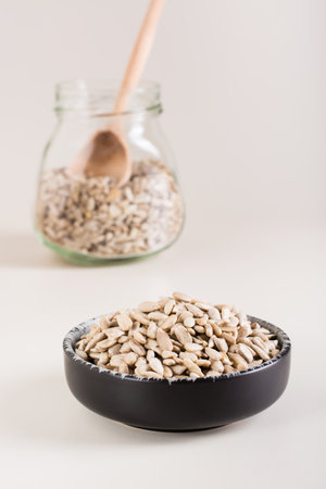 Peeled sunflower seeds in a bowl and in a glass jar on the table. organic food. vertical viewの写真素材