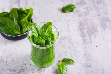 Green spinach smoothie in a glass on a gray background. Health food.の写真素材