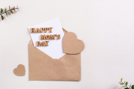 Happy mother's day. Envelope with a sheet, letters and hearts on a light background.