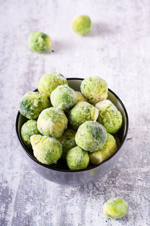 A bowl of frozen brussels sprouts on the table. vegetable diet. web banner. vertical viewの写真素材