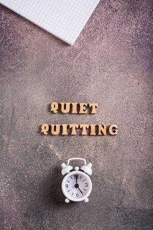 Quiet quitiing wooden letters and an alarm clock. Keeping a balance of life and work. vertical viewの写真素材