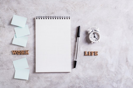 Work life balance concept. Notebook, pen, alarm clock and words on a gray background. top view.の写真素材