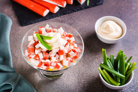 Homemade salad of crab sticks, eggs, chives and corn in a bowl on the tableの写真素材