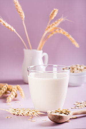 Homemade oat milk in a glass and oatmeal on the table. Alternative to lactose. vertical viewの写真素材