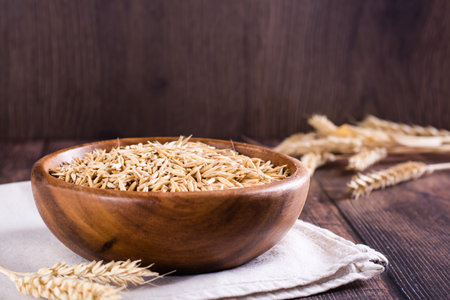 Oat seeds in a wooden bowl and ears on the table. organic harvest.の写真素材