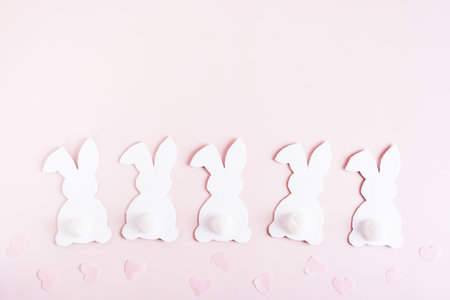 Happy easter white cardboard bunnies in a row and hearts on pink background top viewの写真素材