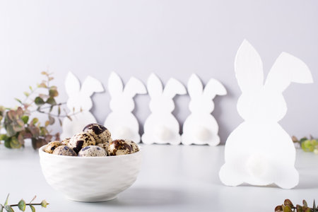 Quail eggs in a bowl and a family of white rabbits on the table for a happy easter.の写真素材