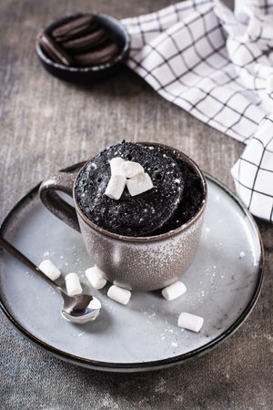 Quick chocolate cake mug with marshmallows on a plate on the table vertical viewの写真素材