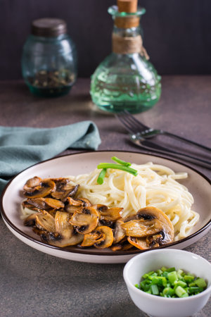 Udon noodles and fried mushrooms on a plate for homemade dinner vertical viewの写真素材