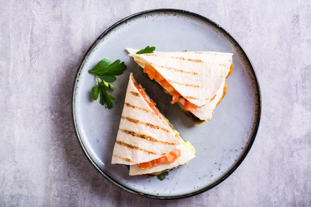 Close up of tortilla with guacamole, fried mushrooms, tomatoes and herbs on a plate top viewの写真素材