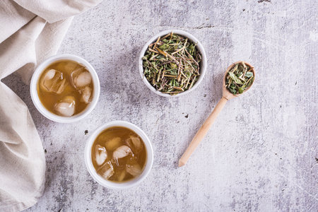 Cold green Japanese hojicha tea with ice in cups and dry tea in a bowl on the table. top viewの写真素材