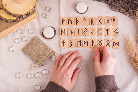Female hands lay out homemade cardboard runes in rows on the table top view