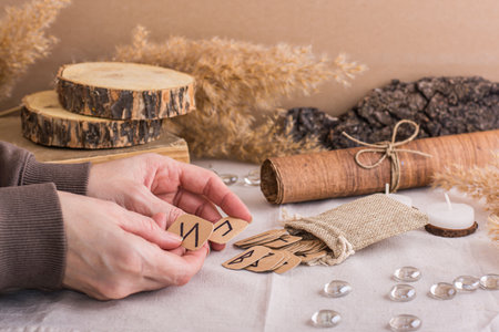 Women's hands are sorting through the Scandinavian divination runes on the tableの写真素材