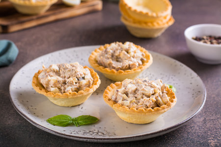 Appetizing tartlets with egg, canned tuna and onion salad on a plate on the tableの写真素材